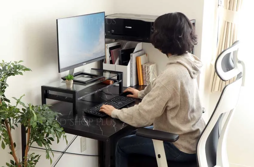 パソコン台を使用してパソコンを打つ女性